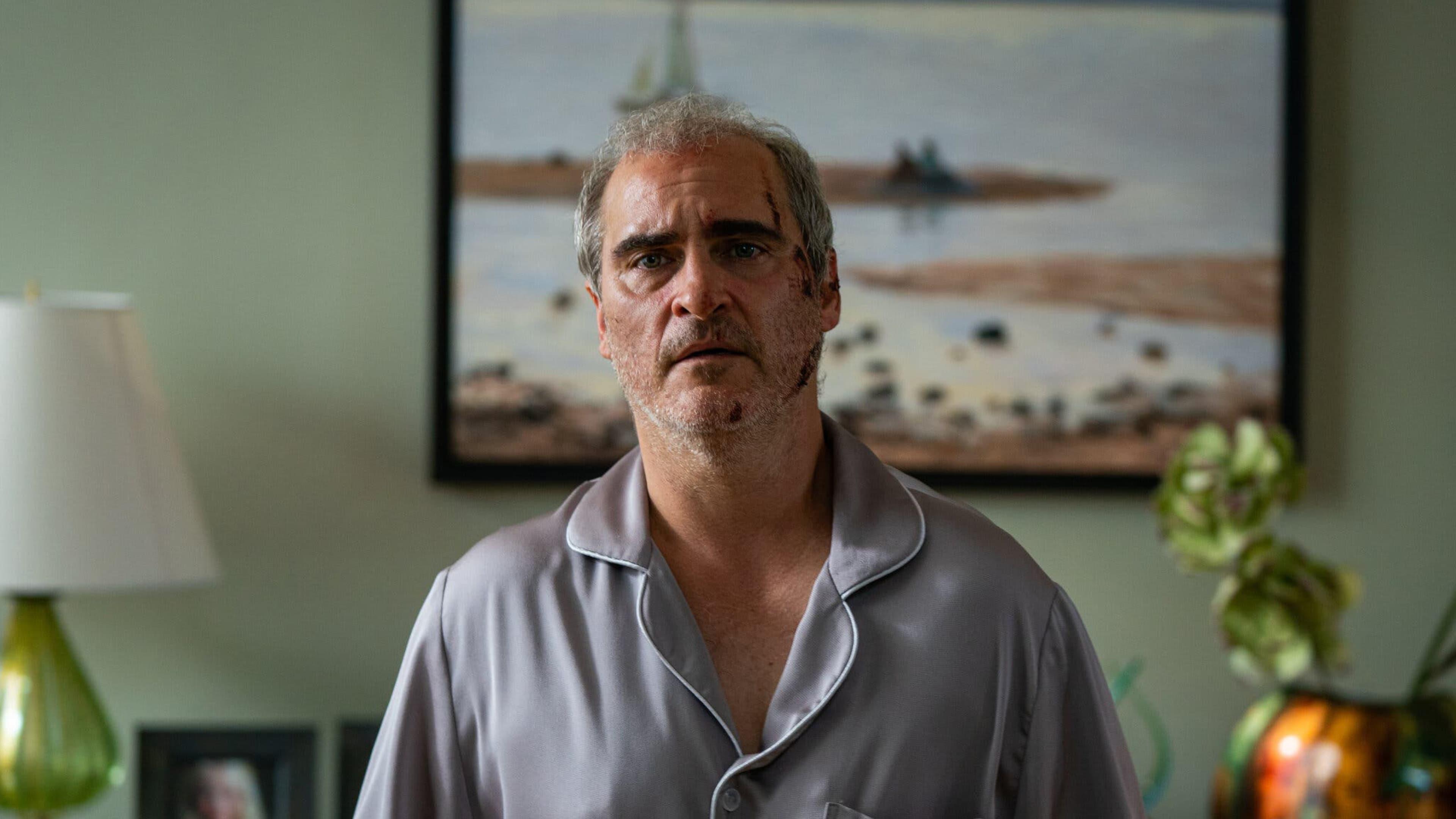 Joaquin Phoenix, battered and bruised, stares blankly at the viewer.