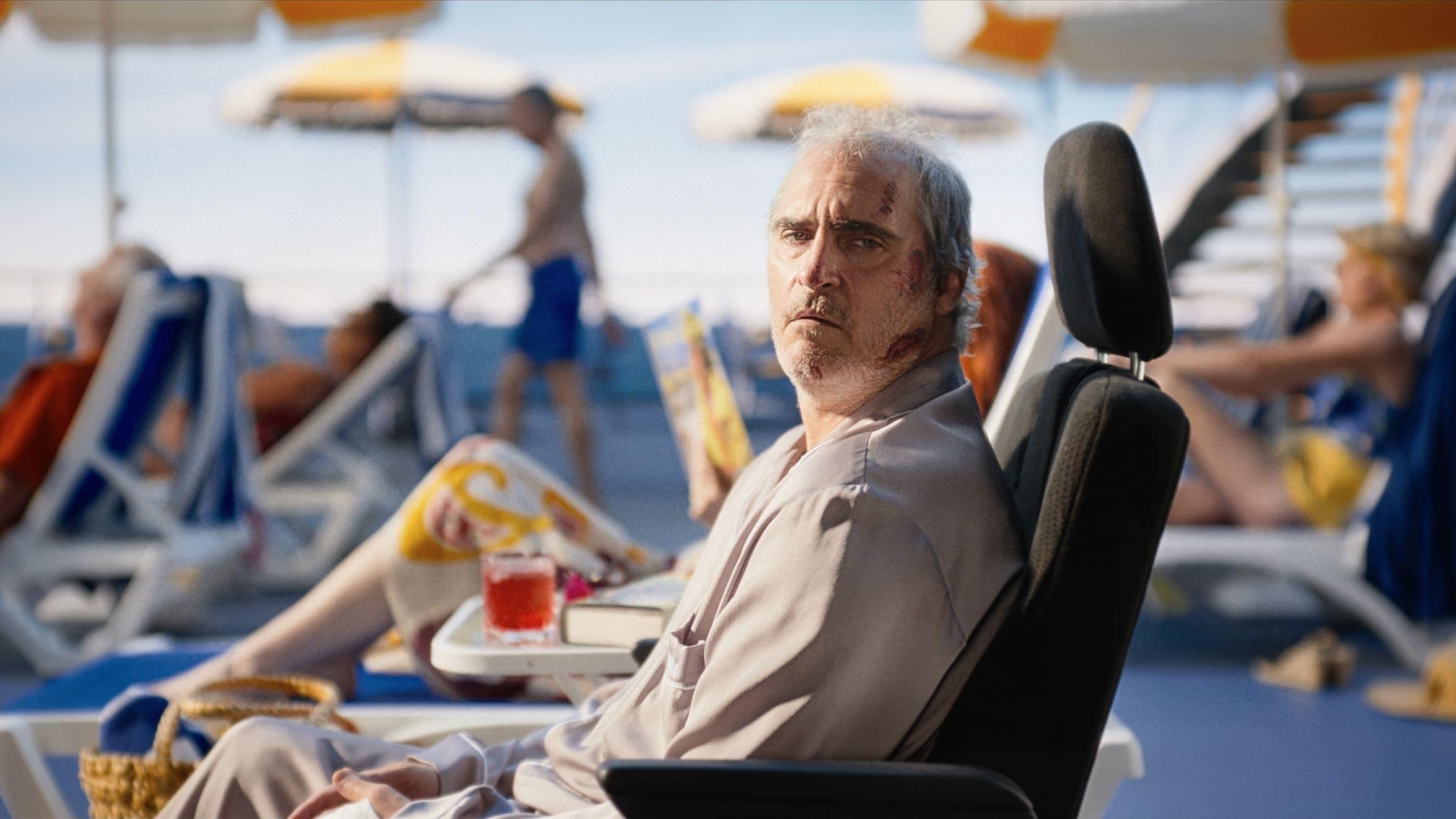 Joaquin Phoenix as Beau reclining on a beach in 'Beau Is Afraid.'
